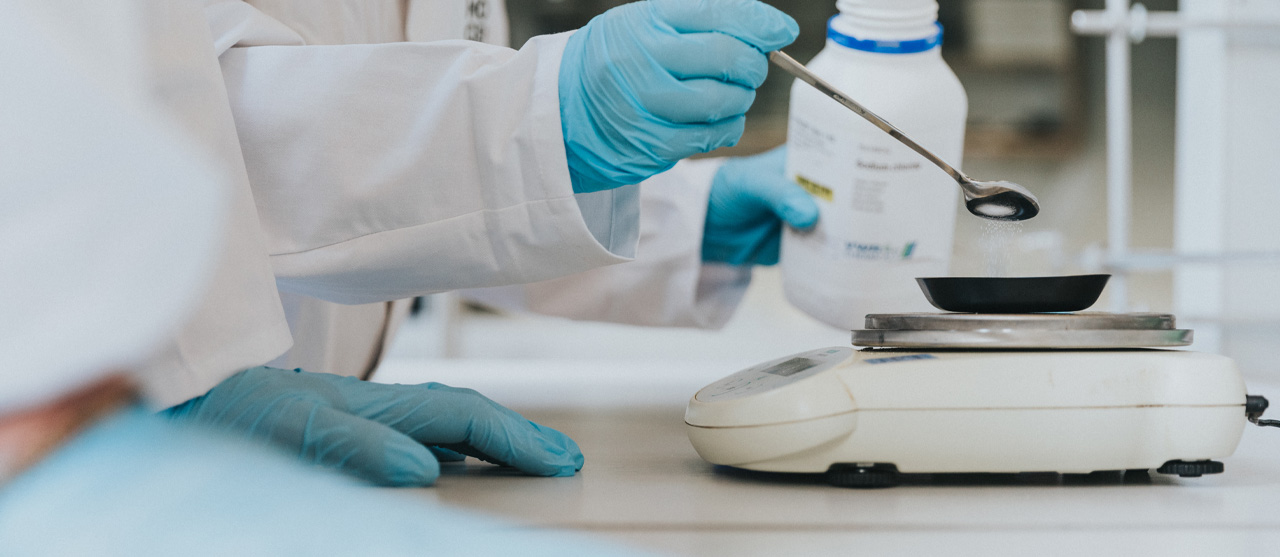 Een student uit de bachelor chemie van HOGENT weegt een chemische stof op een weegschaal.